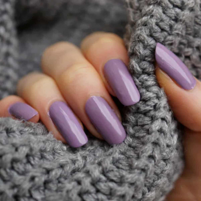 Hand with purple nail polish on a gray textured background.