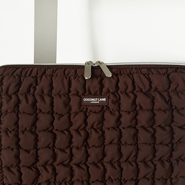 Quilted chocolate brown laptop sleeve with zipper, displayed on a white background.