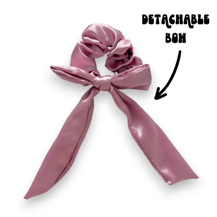 Peony pink satin scrunchie with a detachable bow; arrow label points to the bow.