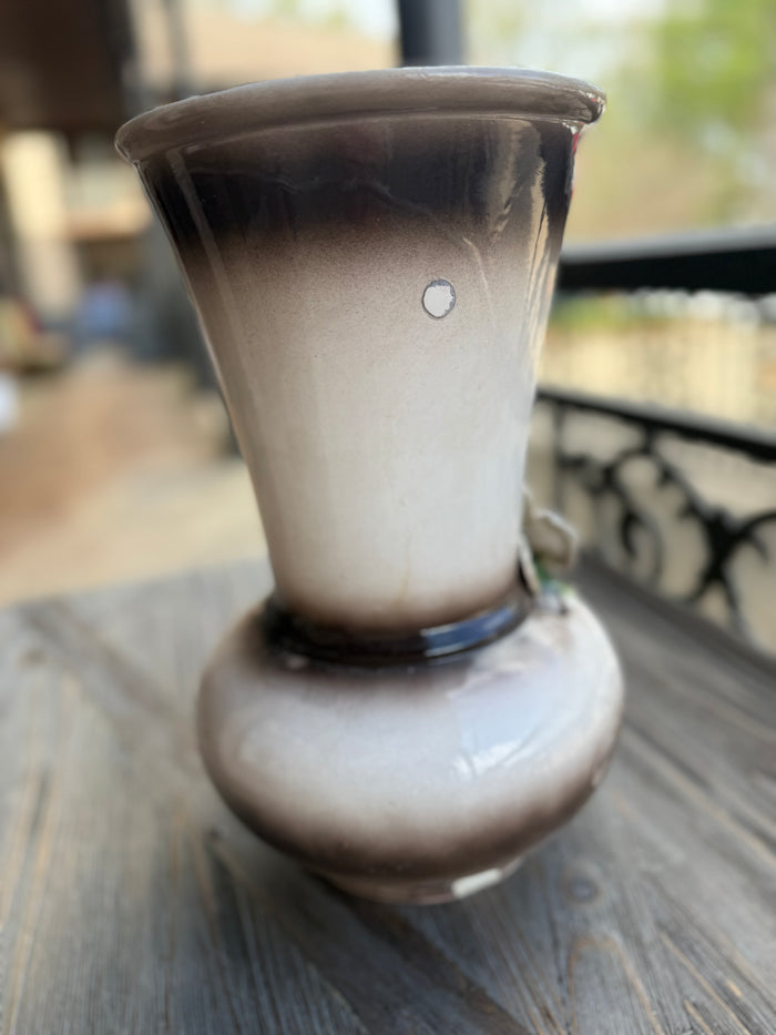 Smoky glass vase on a wooden surface with a blurred outdoor background