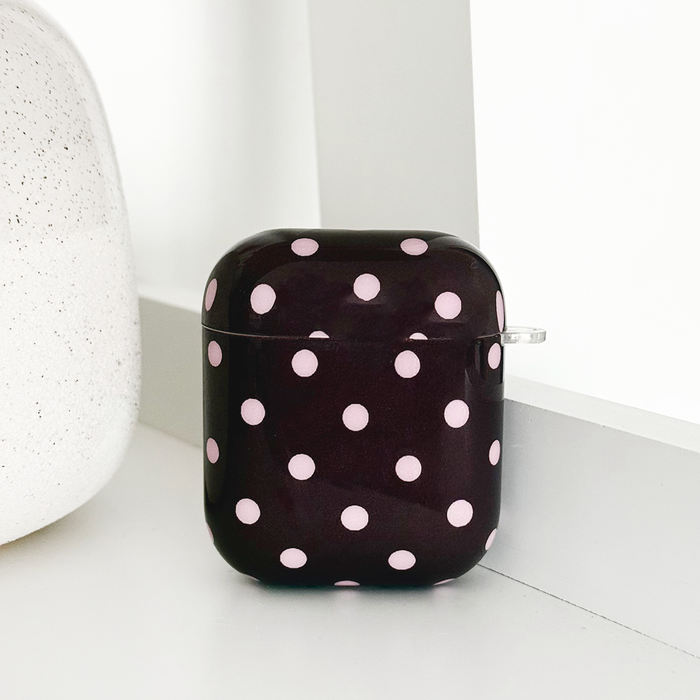 Brown polka dot Coconut Lane AirPods case with clear carabiner on a white surface.