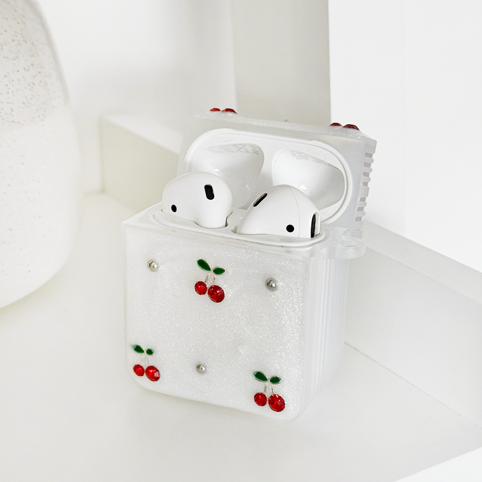 White wireless earbuds in a glittery cherry-patterned Coconut Lane case on a white surface.