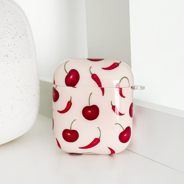 Cherry Spice Coconut Lane AirPods case with red cherry and chili pepper pattern on a white surface.