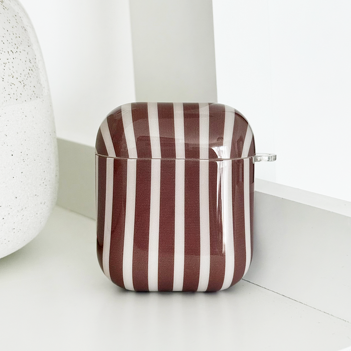 Chestnut striped Coconut Lane Airpods case with TPU protection on a white surface next to a speckled item.