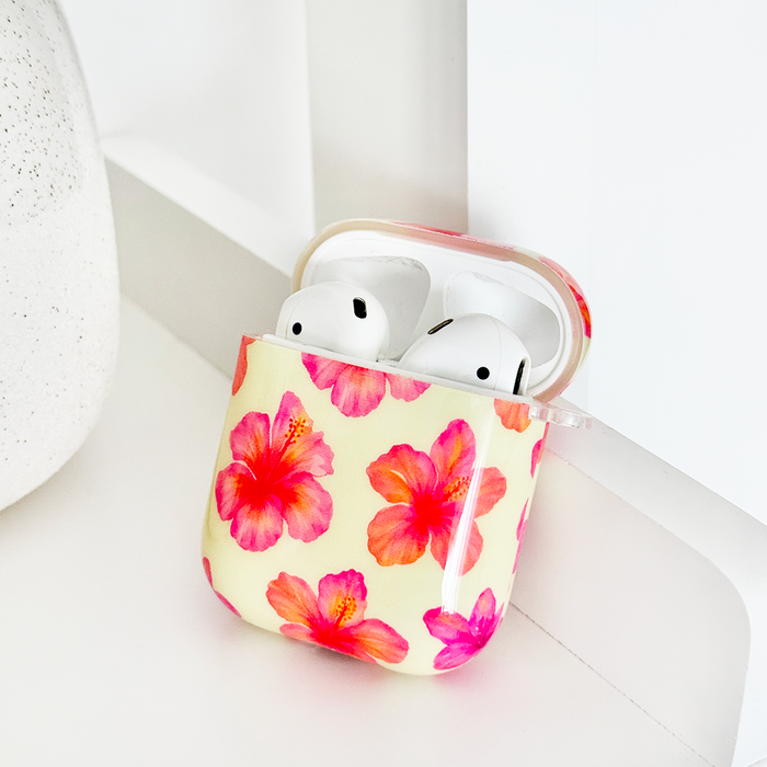 Butter yellow AirPods case with hibiscus pattern from Coconut Lane, resting on a white surface.