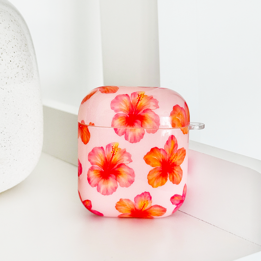 Pink AirPods case with orange-red hibiscus flower pattern and a clear carabiner clip.