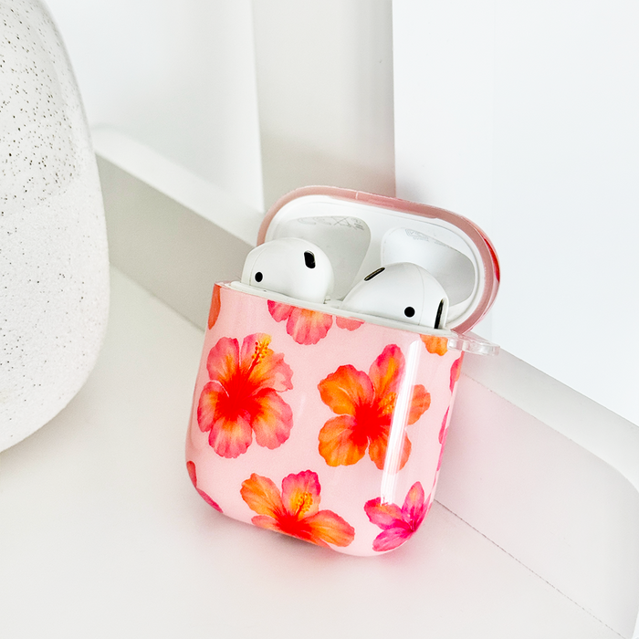 Pink hibiscus-patterned Coconut Lane Airpods case displayed on a white surface.