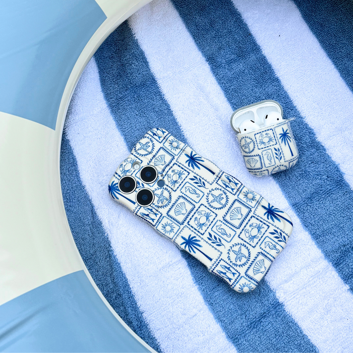 Coconut Lane AirPods case with colorful summer patterns on a striped towel next to a pink pool float.