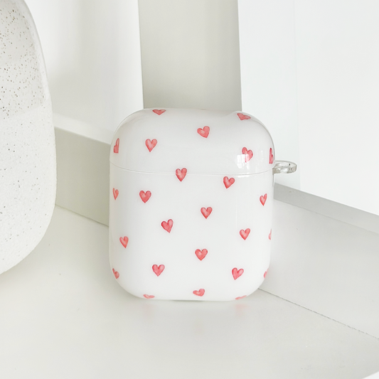 White Coconut Lane Airpods case with a pattern of small red hearts.