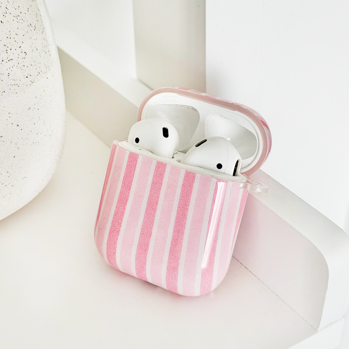 Coconut Lane AirPods case with powder stripe pattern, open to show two white earbuds, on a white surface.