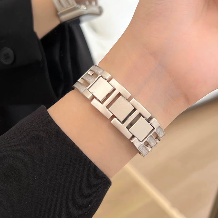 Axiom Link stainless steel Apple Watch band with Greek key cut-out pattern in brushed silver finish on a woman's wrist