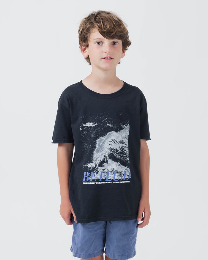 Kingz Be Fluid Youth Tee Black - Front View Youth Model Ocean Wave Graphic Large BE FLUID Text Short Sleeve Casual Fit Streetwear [color:Black]
