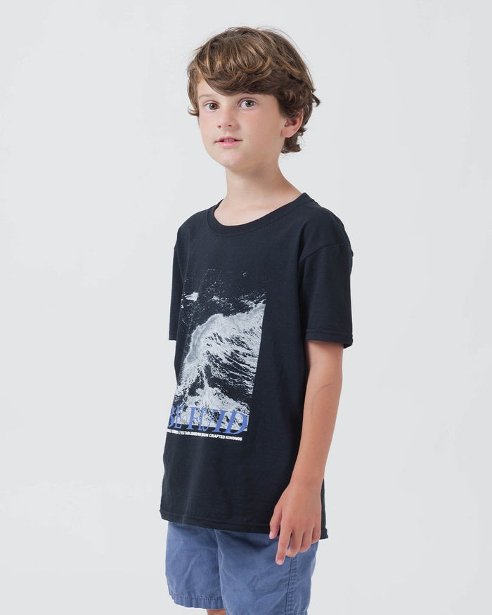 Kingz Be Fluid Youth Tee Black - Side View Young Male Model Black Tee Ocean Wave Graphic Blue BE FLUID Text Casual Streetwear [color:Black]