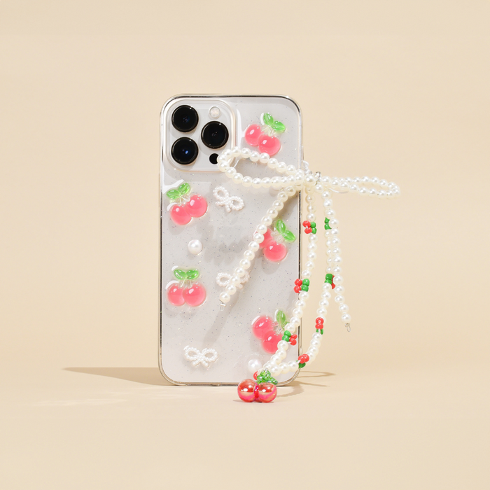 Beaded phone strap with cherry and pearl accents on a clear case with pink cherries, set against a beige background.