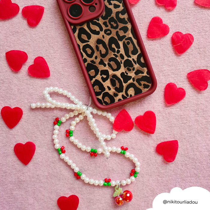 Beaded Cherry Pearl phone strap on a leopard print case, with red hearts and a pink background.