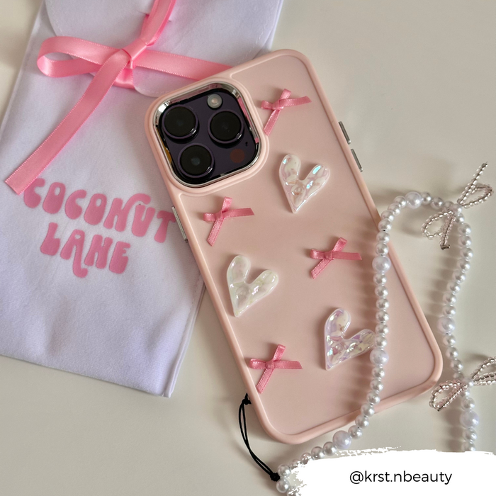Beaded phone strap with mini pearl bows, shown with a pink phone case and pouch in the background.