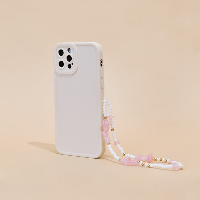 Pink and white beaded phone strap by Coconut Lane on a white case, set against a beige background.
