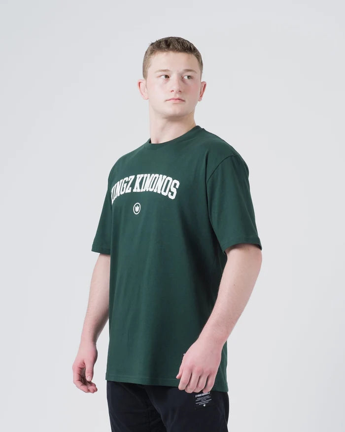 Kingz Collegiate Tee Dark Forest Green - Front View Male Athlete KINGZ KIMONOS Arched White Text Center Chest Small Crown Logo Below Relaxed Fit Short Sleeve BJJ Training Apparel [color:Dark Forest Green]