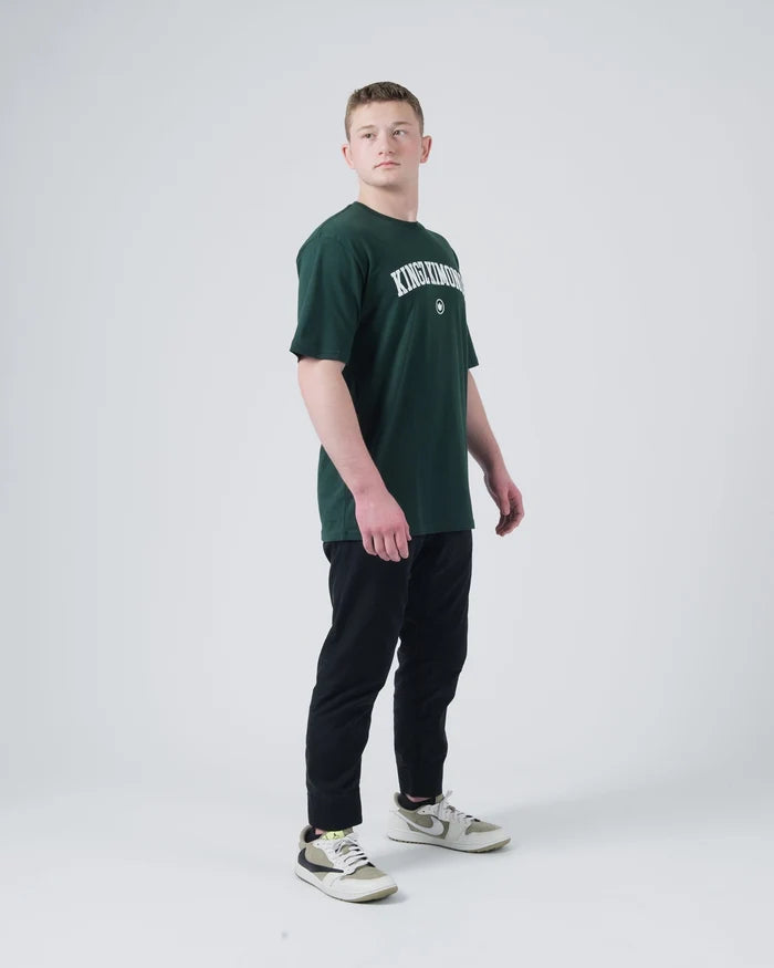 Kingz Collegiate Tee Dark Forest Green - Full Body Side View Male Athlete KINGZ Text Chest Short Sleeve Relaxed Fit Casual BJJ Training Apparel [color:Dark Forest Green]