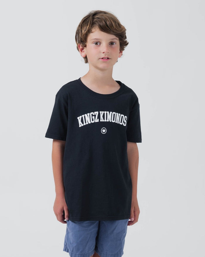Kingz Collegiate Youth Tee Black - Front View Young Male Black Tee White KINGZ KIMONOS Text Centered Crown Logo Streetwear Casual Apparel [color:Black]