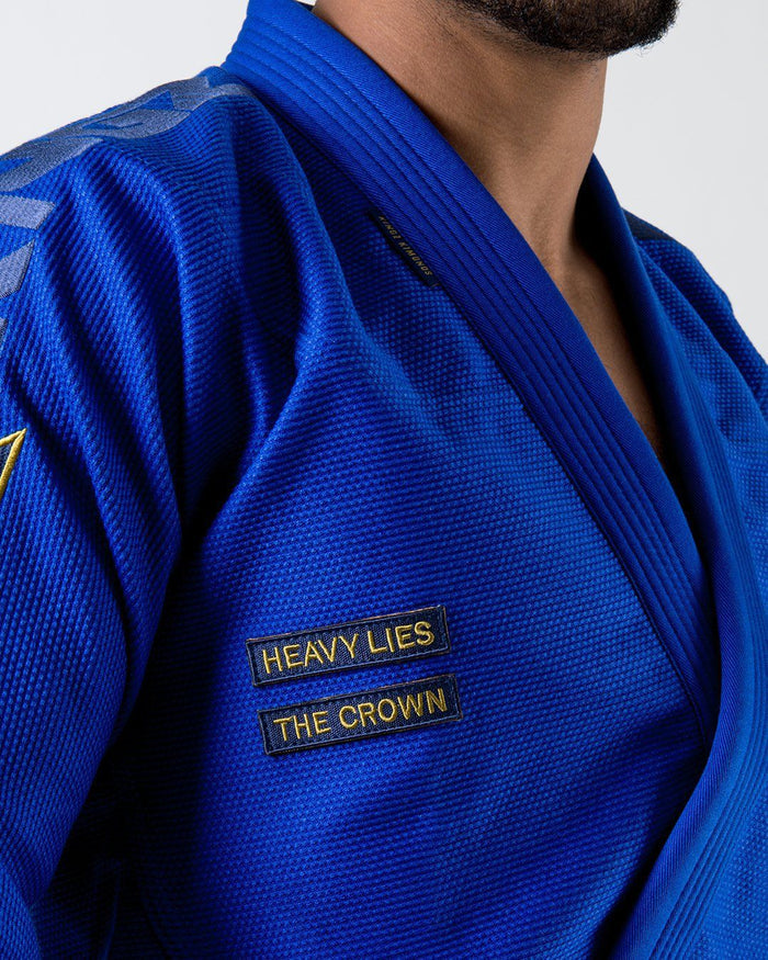 Kingz Comp 450 V6 Gi - Blue - Close-Up Detail View Embroidered "HEAVY LIES THE CROWN" Text Bold Blue Weave Texture Reinforced Collar Jiu Jitsu Gear [color:Blue]