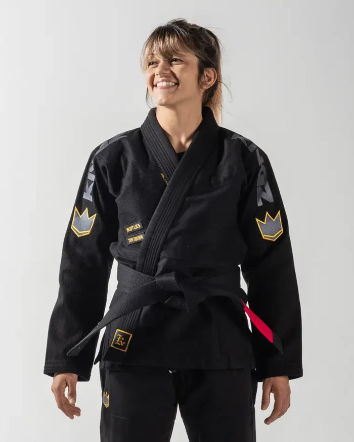 Kingz Comp 450 V6 Women's Gi Black - Front View Female Athlete Black Gi Yellow Crown Patches Left Arm Chest Logo Text Embroidered Details Durable Weave BJJ Gi Training [color:Black]