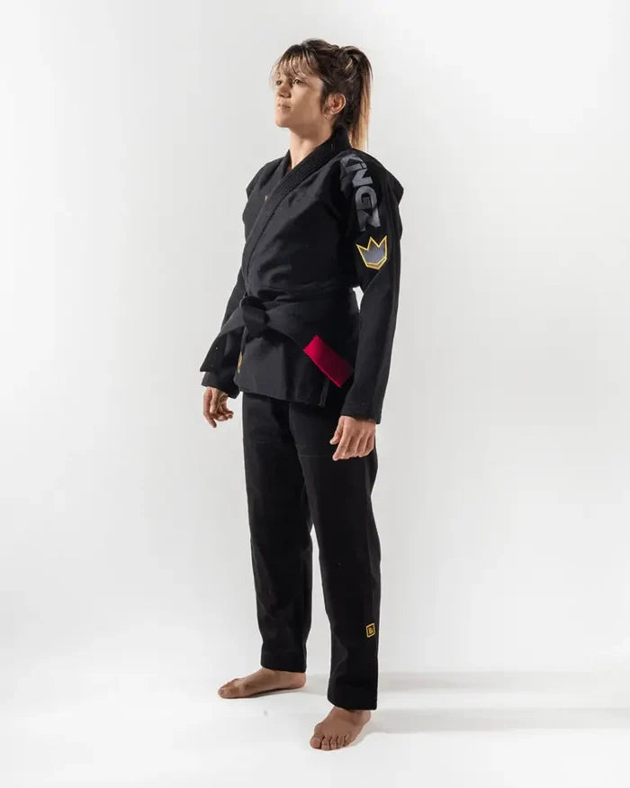 Kingz Comp 450 V6 Women's Gi - Black - Full Body Side View Female Athlete Black Gi White KINGZ Shoulder Text Gold Crown Sleeve Badge Red Side Panel BJJ Training Gi [color:Black]