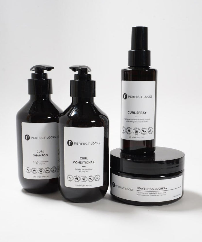 Four Perfect Locks curl shampoo, conditioner, spray, and leave-in cream on a white surface in sleek minimalist packaging.