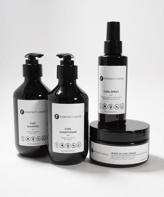 Four Perfect Locks curl shampoo, conditioner, spray, and leave-in cream on a white surface in sleek minimalist packaging.
