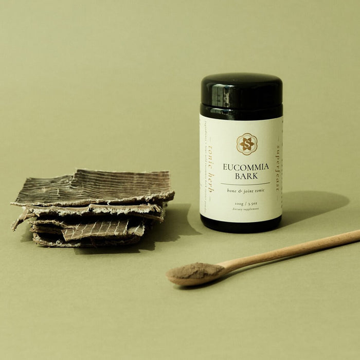 Eucumbia bark and a container of Eucommia bark powder on a green background