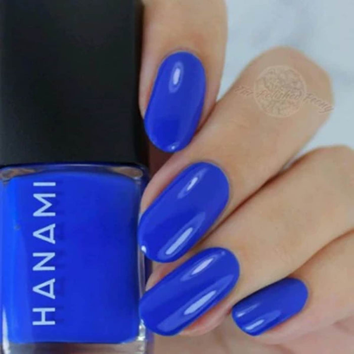 Hand with blue nail polish holding a bottle of HANAMI nail polish.