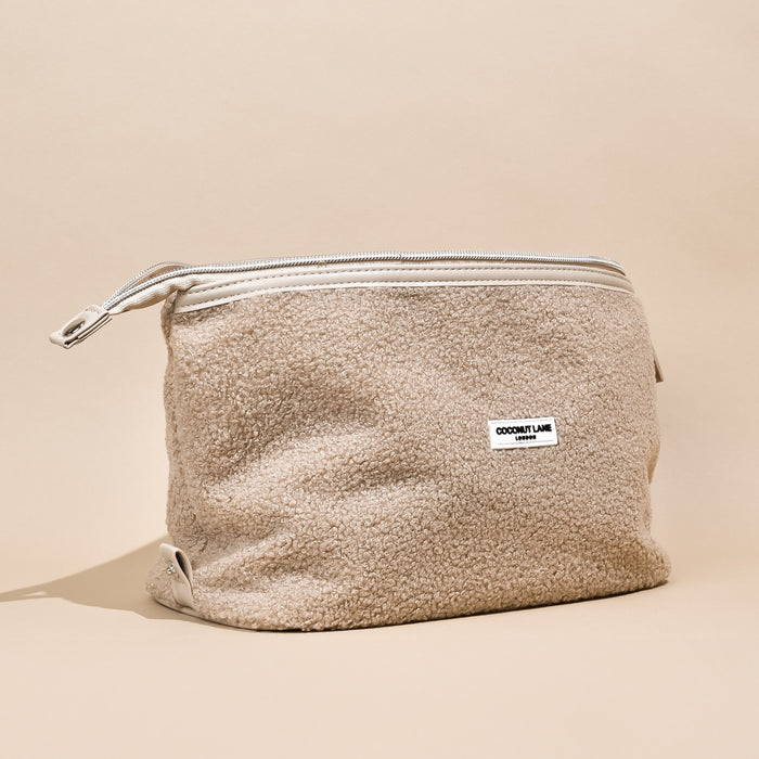 Beige boucle expandable makeup bag with silver zip and white leather trim.