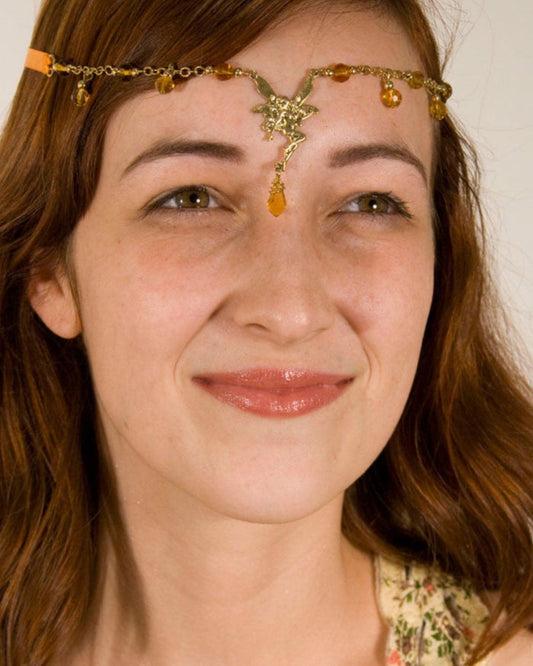 Model wearing Fairy Tie-On Crown gold ribbon crown and necklace featuring a fairy centerpiece, amber crystal dangles, and tie-on ribbon design, front view.