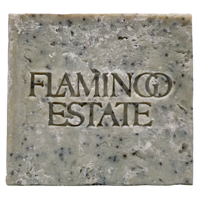 A single rectangular bar of handmade soap with a rustic, textured surface speckled with dark flecks. The brand name 'FLAMINGO ESTATE' is embossed in the center of the soap.