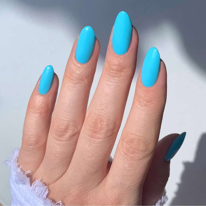 Hand with blue nail polish on a light background.