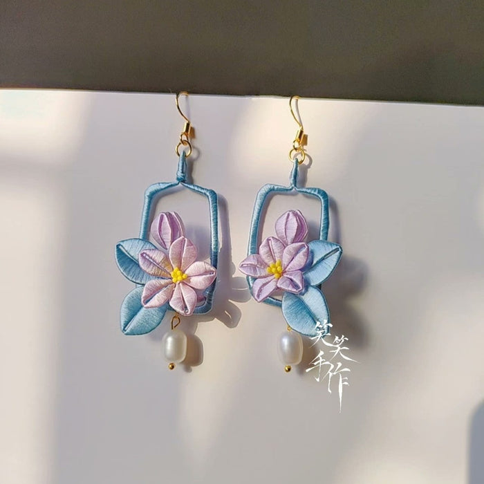 Close-up shot of the handmade Chanhua flower earrings, highlighting the intricate textile craftsmanship, 925 silver hooks, and lustrous white freshwater pearls.