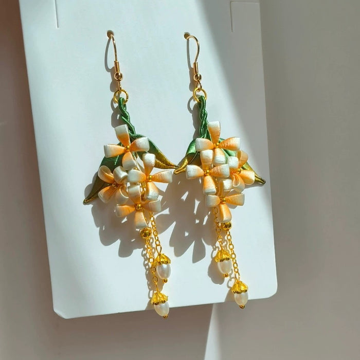 A pair of handcrafted Chanhua floral earrings with pearl and chain accents, shown on a white display card.