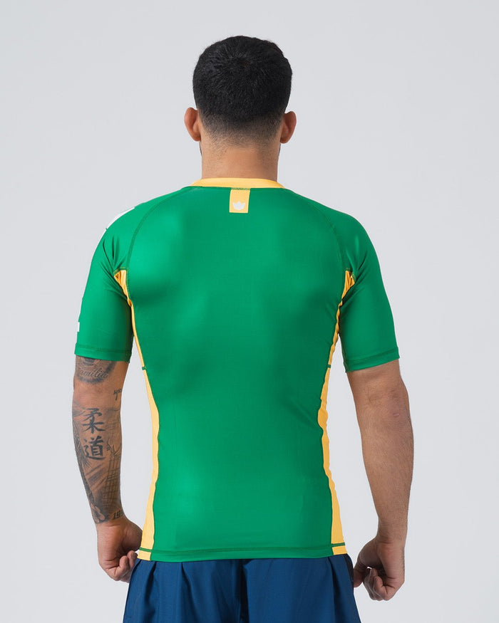 Kingz Jersey Rashguard Australia Edition - Full Body Back View Male Athlete Short Sleeve Green Body Yellow Gold Crown Logo Upper Back Yellow Gold Side Stripes Both Sides Australian Colors Blue Shorts BJJ National Pride Training [color:Green/Austria]