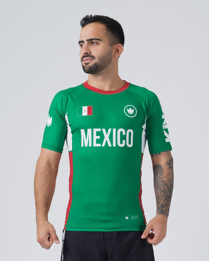 Kingz Jersey Rashguard Mexico Edition - Full Body 3/4 Front View Male Athlete Short Sleeve Green Body MEXICO White Bold Chest Text Mexican Flag Patch White Crown Logo Circle Red Collar Red Side Stripes White KINGZ Sleeve Text BJJ [color:Green/Mexico]