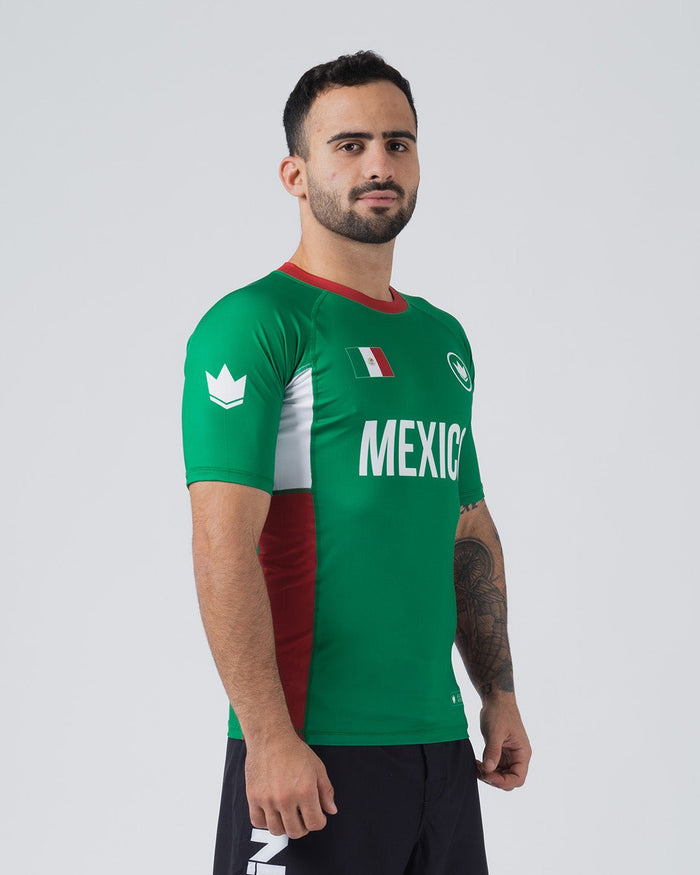 Kingz Jersey Rashguard Mexico Edition - Full Body 3/4 Right Side View Male Athlete Short Sleeve Green MEXICO Text White Side Panel Red Stripe Right Side Mexico Flag White Crown Logo Red Collar BJJ National Pride Sport [color:Green/Mexico]