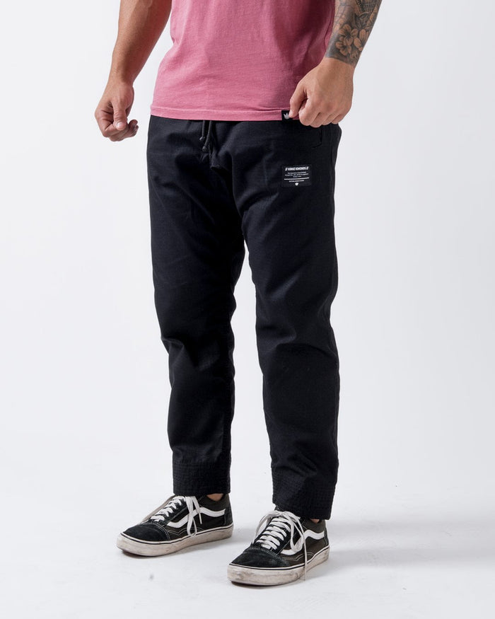 Kingz Casual Rip Stop Gi Pant Black - Front View Male Athlete Black Rip Stop Fabric White Logo Patch Left Thigh Drawstring Waist Relaxed Fit BJJ Gi Training [color:Black]
