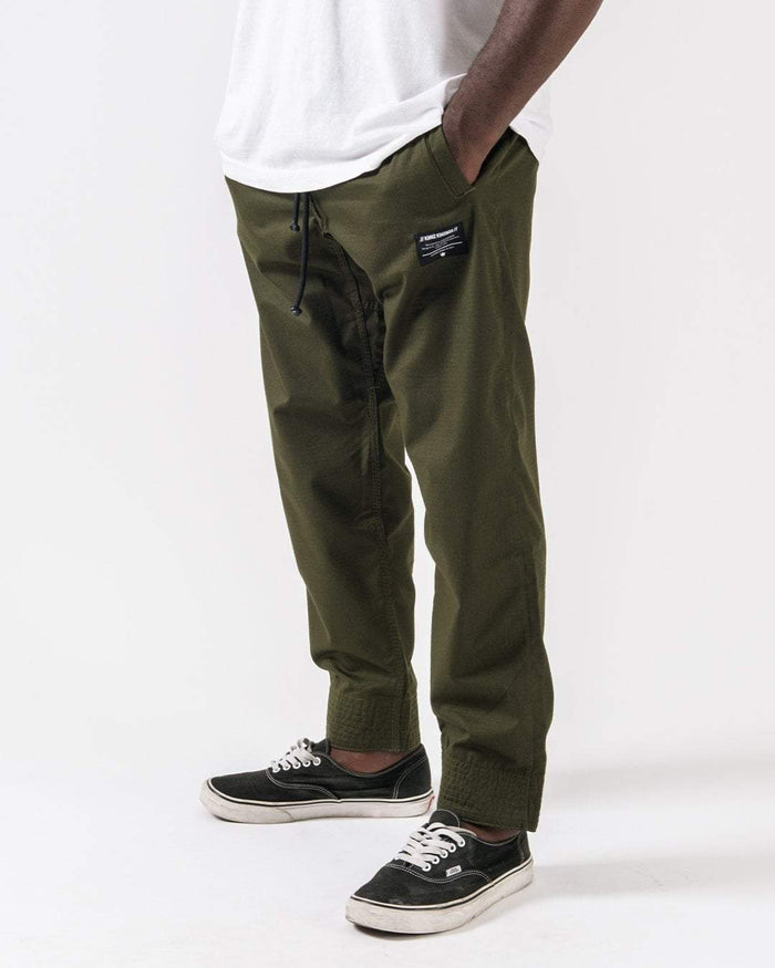 Kingz Casual Rip Stop Gi Pants Military Green - Lower Body Side View Male Model Elastic Cuffs Black Drawstring Waist Kingz Patch Right Thigh Durable Fabric BJJ Gi Training [color:Military Green]