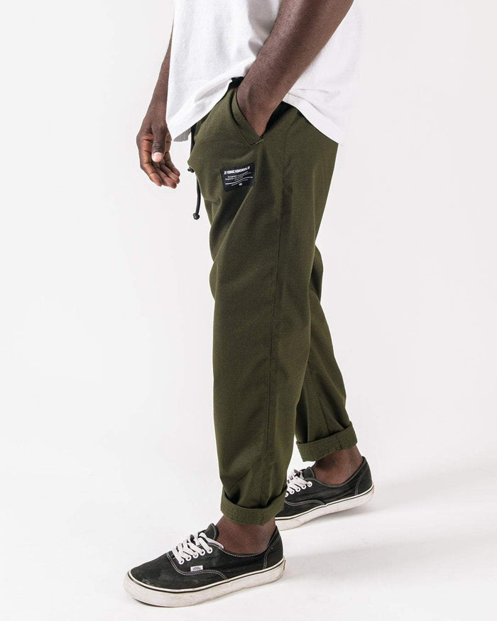 Kingz Casual Rip Stop Gi Pants Military Green - Side View Male Model Relaxed Fit Drawstring Waist Black Patch Detail Cuffed Ankles Durable Fabric BJJ Training Gi Pants [color:Military Green]