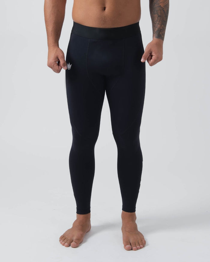 Kingz Kore Grappling Spats Black - Full Body Front View Shirtless Tattooed Male Athlete All-Black High-Waist Small White Crown Logo Left Thigh Bare Feet Full-Length Compression Fit Men's No-Gi BJJ Spats Kore Collection [color:Black]