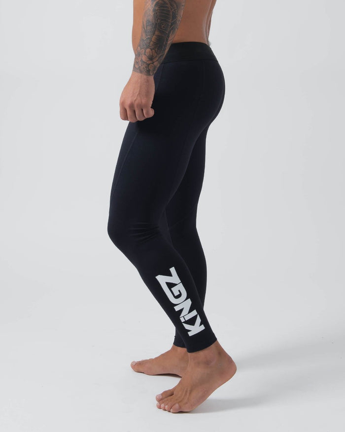 Kingz Kore Grappling Spats Black - Full Body Left Side Profile Shirtless Tattooed Male Athlete All-Black KINGZ Large Bold White Vertical Text Right Calf Full-Length Compression Fit Men's No-Gi BJJ Spats Kore Collection [color:Black]