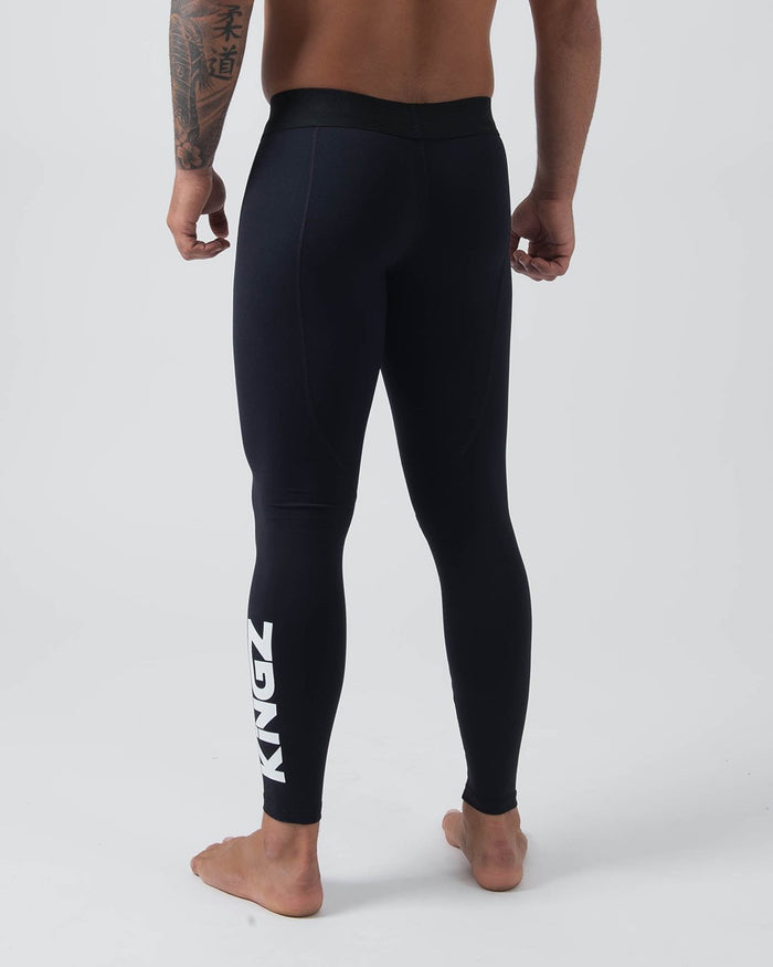 Kingz Kore Grappling Spats Black - Full Body Back View Shirtless Tattooed Male Athlete All-Black KINGZ Large Bold White Vertical Text Right Calf Men's No-Gi BJJ Spats Kore Collection [color:Black]
