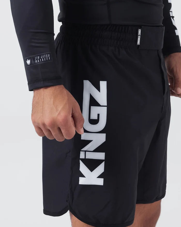 Kingz Kore V2 Shorts Black - Close Up Left Thigh Side View Large KINGZ White Vertical Text Left Outer Thigh KINGZ KIMONOS Elastic Waistband JIU JITSU ROYALTY Crown Patch Sleeve Black Lightweight Grappling Fabric Men's No-Gi BJJ MMA Kore Collection [color:Black]