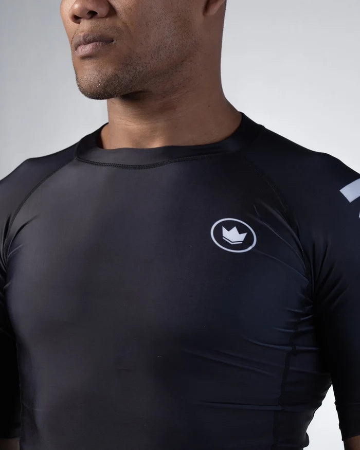 Kingz Kore V2 Short Sleeve Rashguard Black - Close-Up Front View Male Athlete Black Crown Badge Left Chest Sleek Fit Raglan Sleeves Smooth Fabric BJJ Training Rash Guard [color:Black]