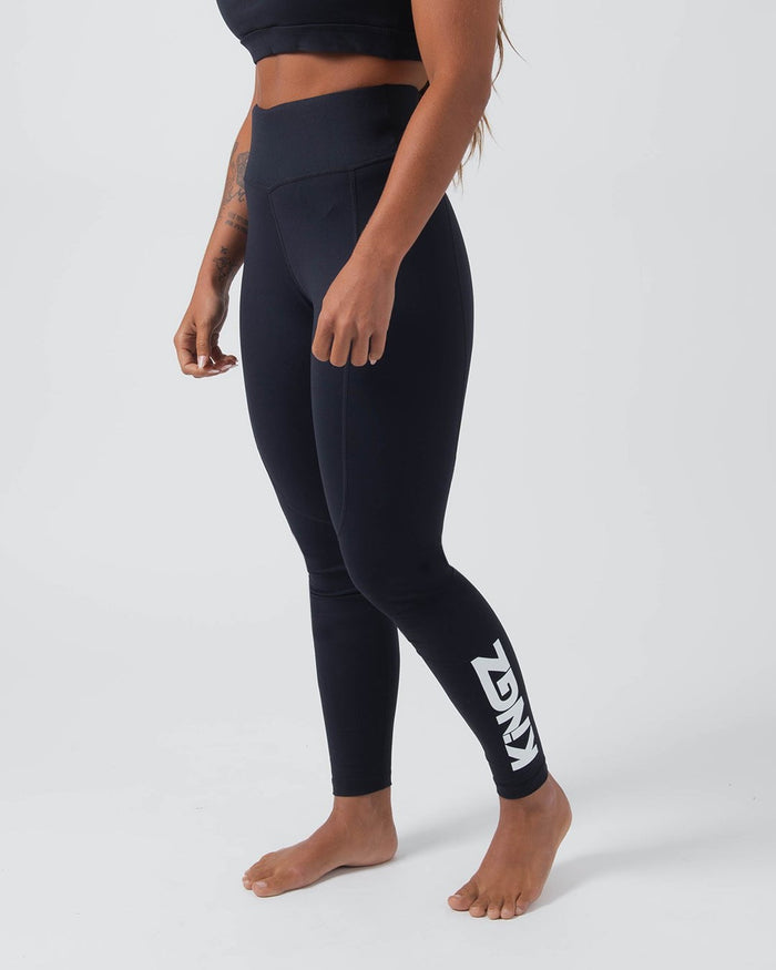 Kingz Kore Women's Grappling Spats Black - Full Body Right Side Profile Tattooed Female Athlete All-Black KINGZ Large White Vertical Text Right Calf High-Waist Bare Feet Women's No-Gi BJJ Spats Kore Collection [color:Black]