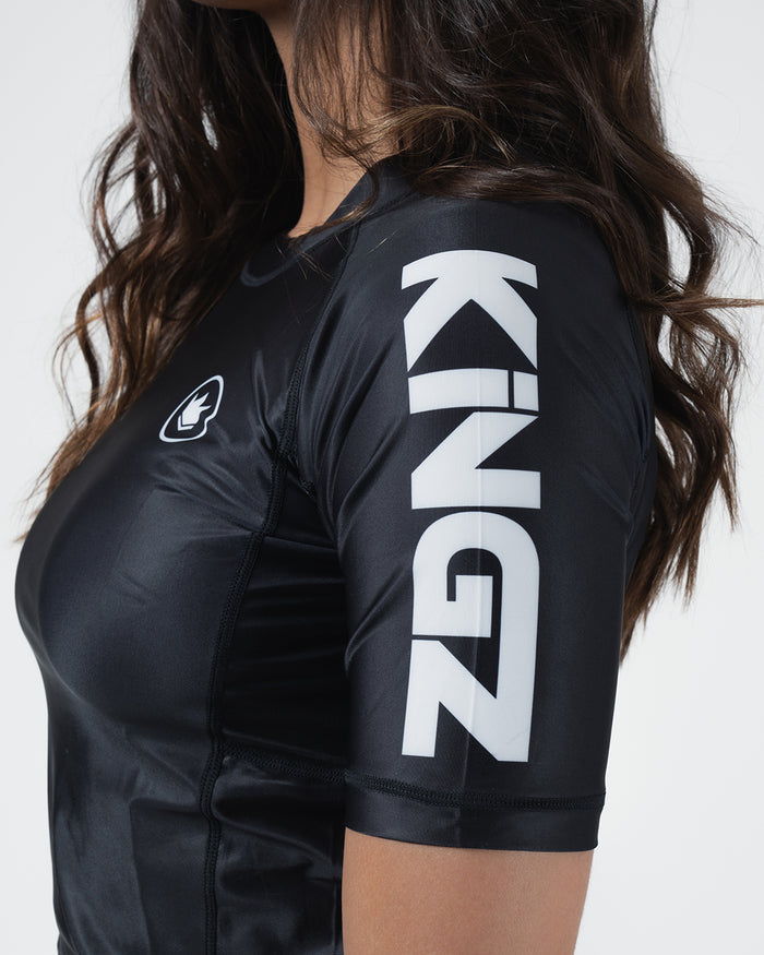 Kingz Kore V2 Short Sleeve Rashguard Black - Close Up Sleeve Detail KINGZ Bold White Oversized Text Sleeve Black Body JIU JITSU ROYALTY Crown Badge Left Chest Sublimated Graphics Women's BJJ Kore Collection Performance [color:Black]